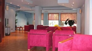 Un vestíbulo espacioso con suelo de madera, zona de estar en rojo y ventanas amplias que dejan entrar luz natural.