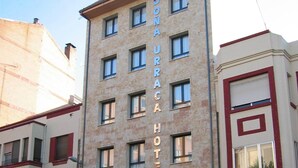 Un edificio de hotel con varios pisos, un cartel que indica que es un hotel y banderas afuera.