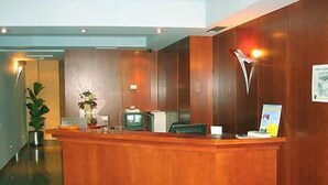 Una recepción con detalles de madera, un televisor verde y una planta.