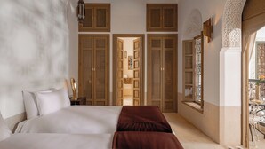 A bedroom with a large bed, wooden doors, and a window with a view. - Riad Jaaneman (Marrakech)