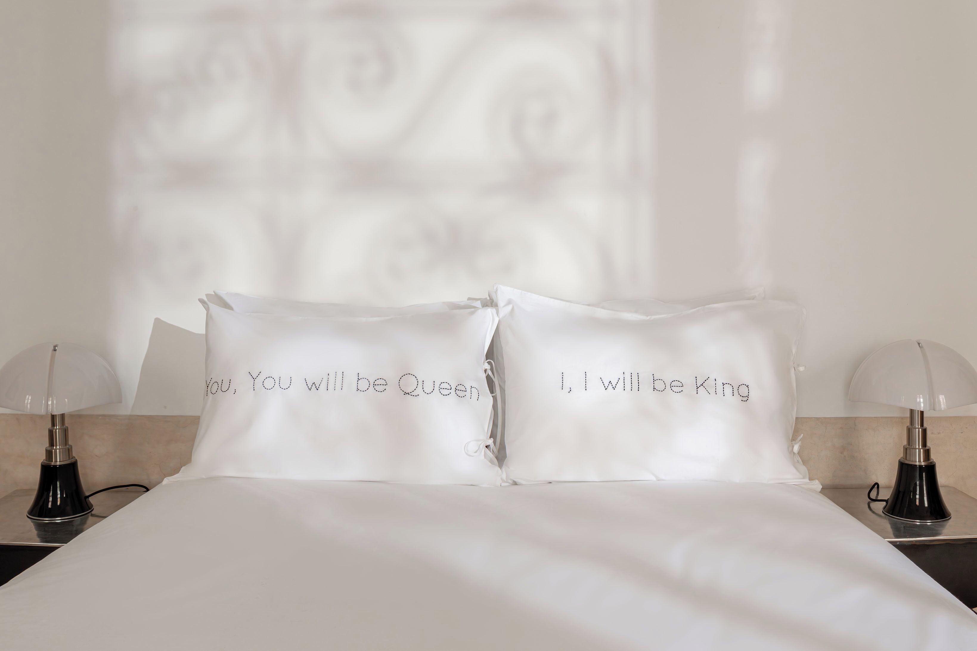 A neatly made bed with two pillows, each with a printed message.