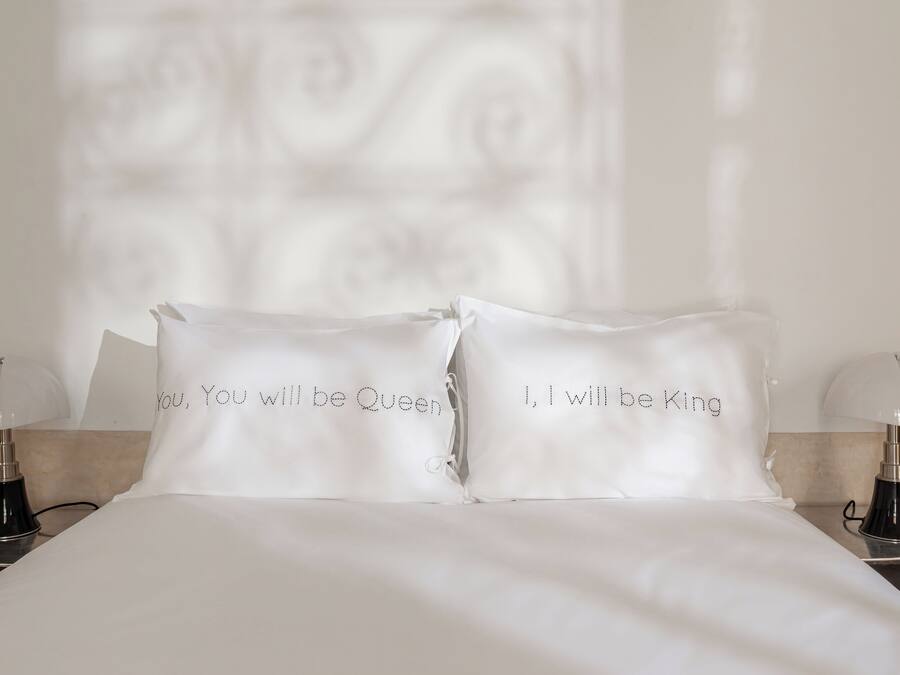 A neatly made bed with two pillows, each with a printed message.