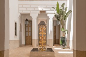 A hallway with a central water feature, a large potted plant, and ornate wall decorations. - Riad Jaaneman (Marrakech)