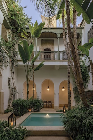 A courtyard with a pool, palm trees, and a two-story building with balconies. - Riad Jaaneman (Marrakech)