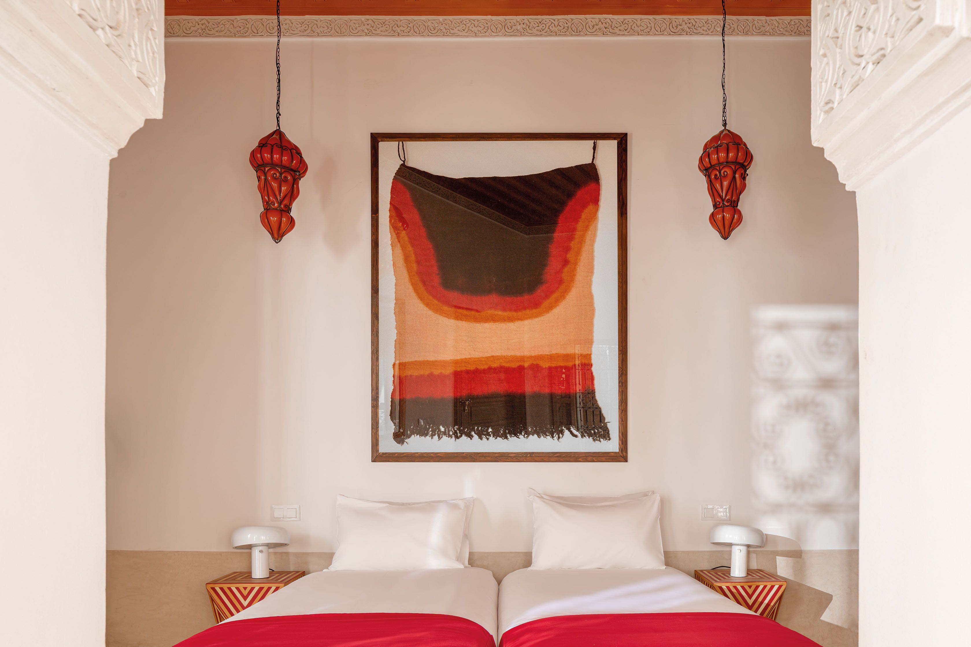 Una habitación de hotel con una cama, dos mesitas de noche y una obra de arte colgada en la pared.