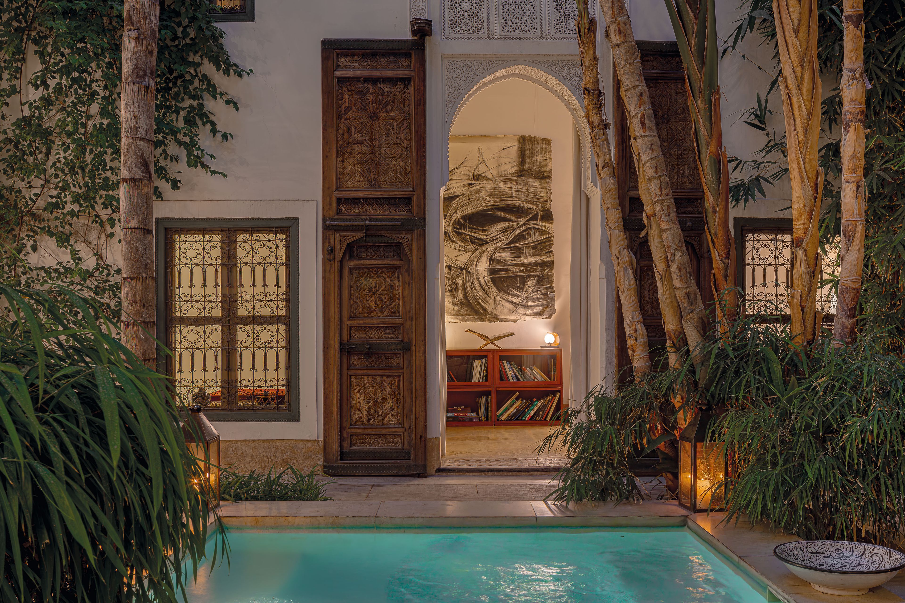 A pool area with a wooden door, bookshelves, and a large arched doorway.