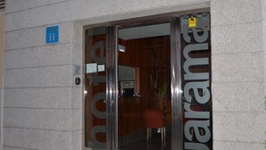 A hotel entrance with a glass door and a visible interior including a reception desk and seating area. - Hotel Jarama (Zamora)