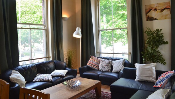 A living room with two black leather sofas, a wooden coffee table, and a large window with curtains. - Metrostays - O'Connell Street 84-1 (Dublin)