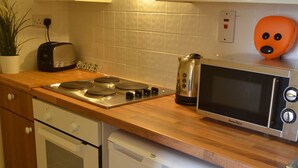 Una cocina compacta con armarios de madera, un tostador, un microondas, un hervidor y un lavavajillas.