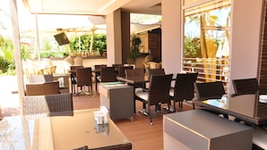 A restaurant with wicker furniture, a bar area, and a view of greenery. - Vega Green Apart Hotel (Alanya)