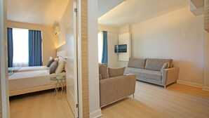 A modern hotel room with a bed, a small table, a sofa, and a TV. - Vega Green Apart Hotel (Alanya)
