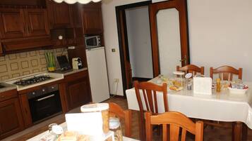 Una cocina con armarios de madera, un microondas y una mesa de comedor para cuatro.