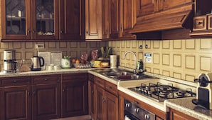 Une cuisine avec des meubles en bois, une cuisinière à gaz, un évier et divers appareils de cuisine.