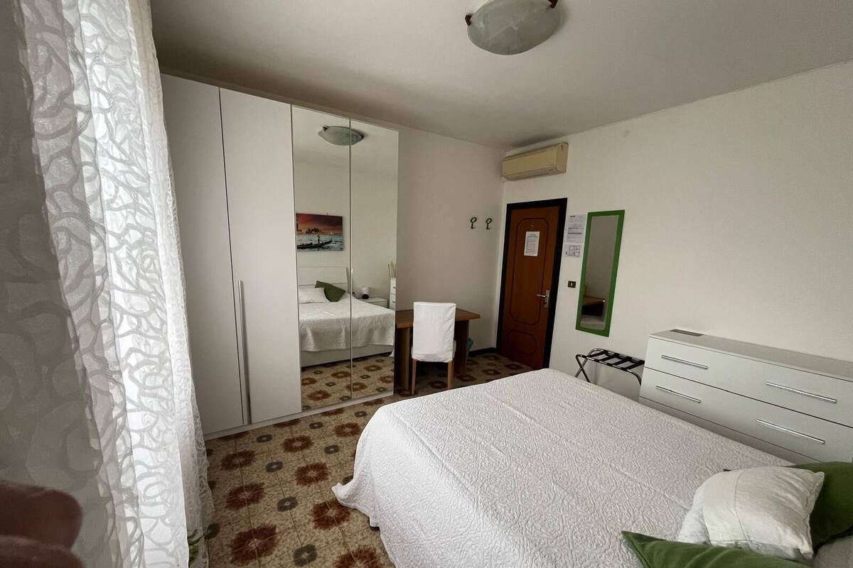 Une chambre d’hôtel avec un lit, une armoire, un bureau et un miroir.