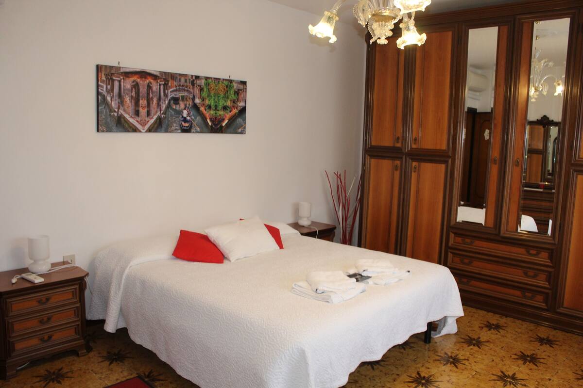 Une chambre d’hôtel avec un lit, une table de chevet, une commode, un miroir et un tableau au mur.