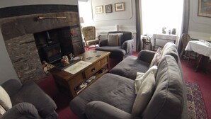 Una sala de estar con chimenea, sofás, una mesa de centro y un comedor con mesa y sillas.