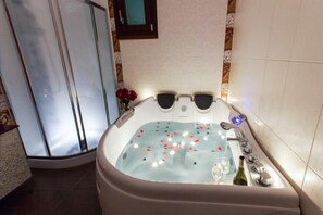 A bathroom with a large bathtub, a glass shower enclosure, and a mirror on the wall. - Alyko Villas (Naxos)