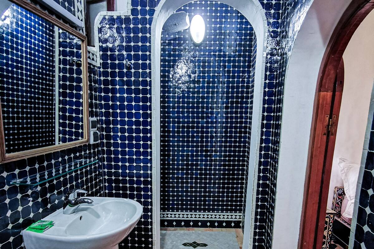 Un baño con lavamanos, paredes de azulejos y zona de ducha.