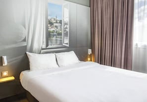Una habitación de hotel con una cama grande, un ventanal con vistas a la ciudad y una cortina.