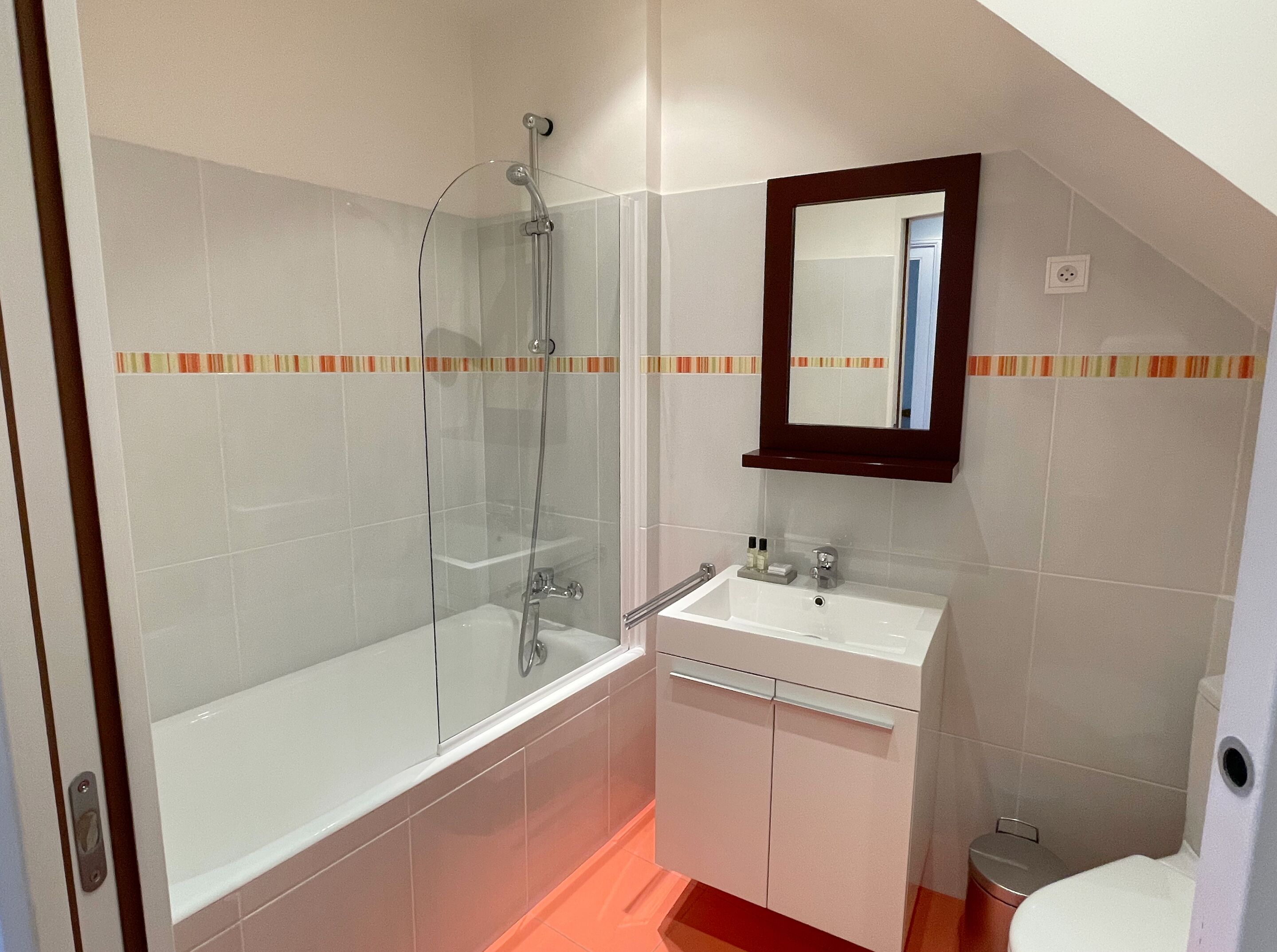 A bathroom with a glass-enclosed shower, a white sink with a mirror above it, and a toilet.