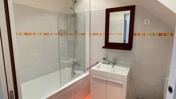 A bathroom with a glass-enclosed shower, a white sink with a mirror above it, and a toilet.