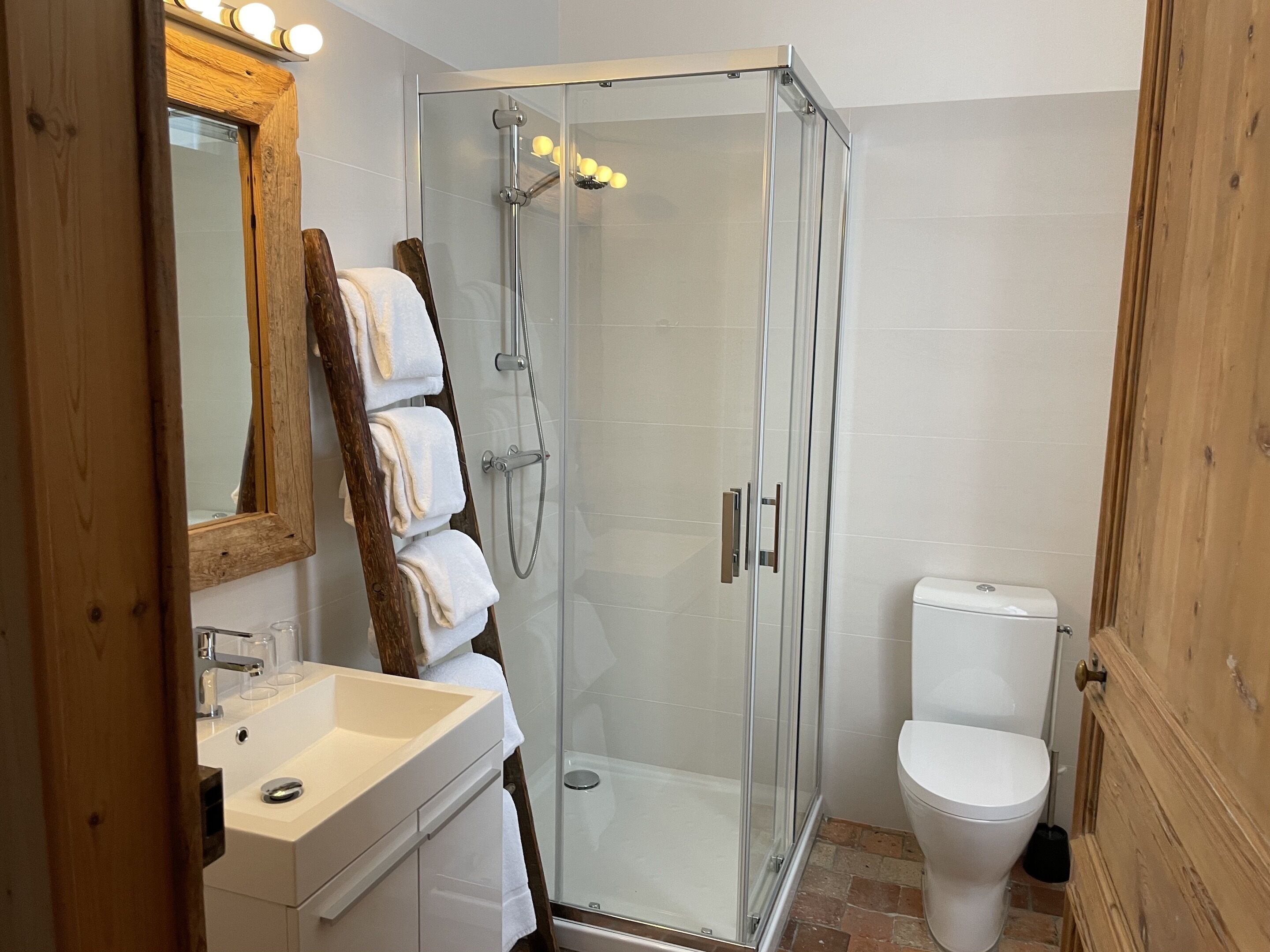 Un baño moderno con ducha de vidrio, lavamanos blanco y retrete.