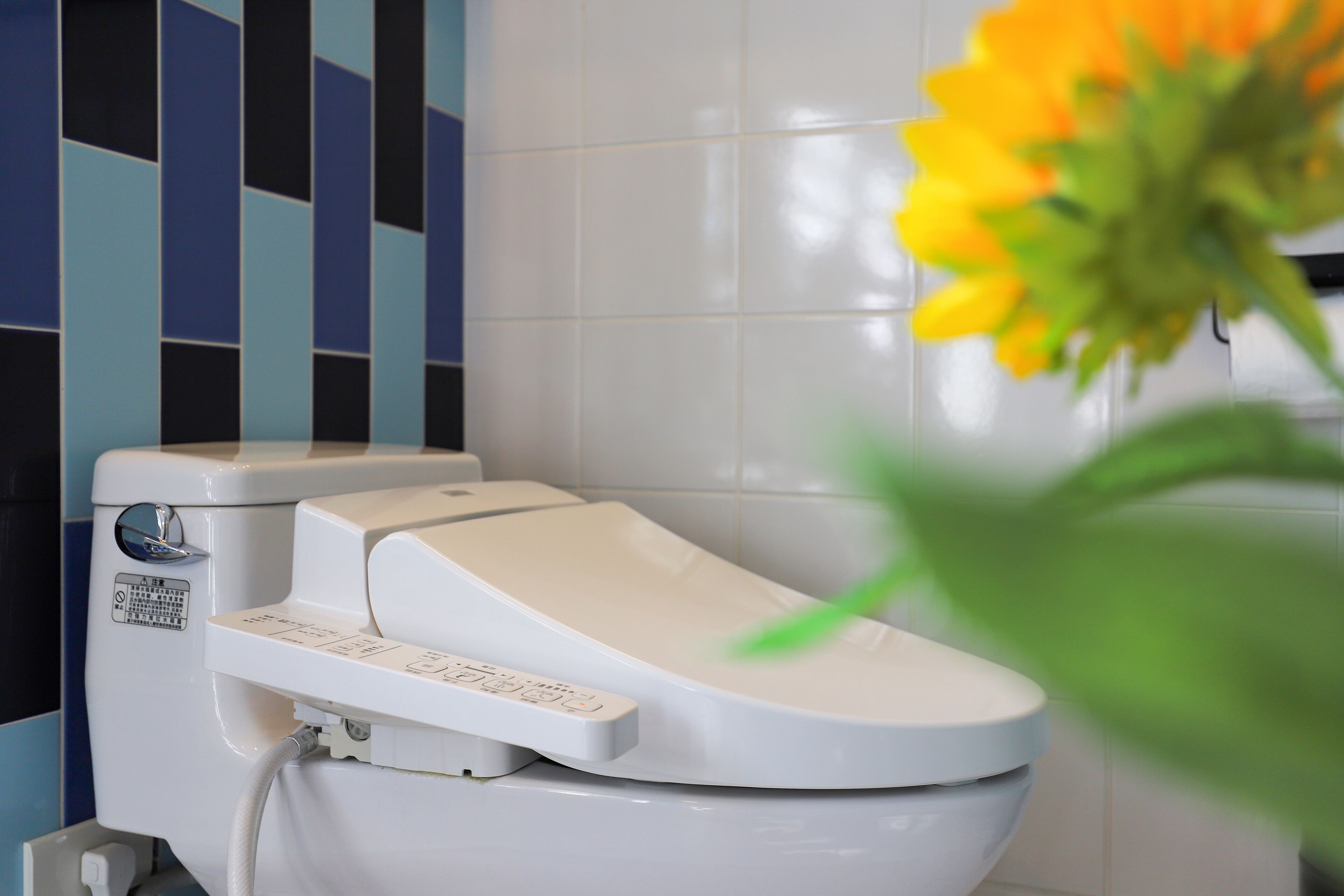 A modern toilet with a control panel and a bidet attachment.
