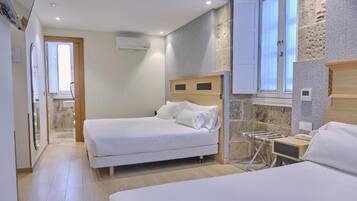 Een hotelkamer met twee bedden, een accentmuur van steen, een houten hoofdeinde en een raam met gordijnen.