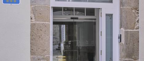 A hotel entrance with a stone facade, a glass door, and a sign indicating it is a hotel.