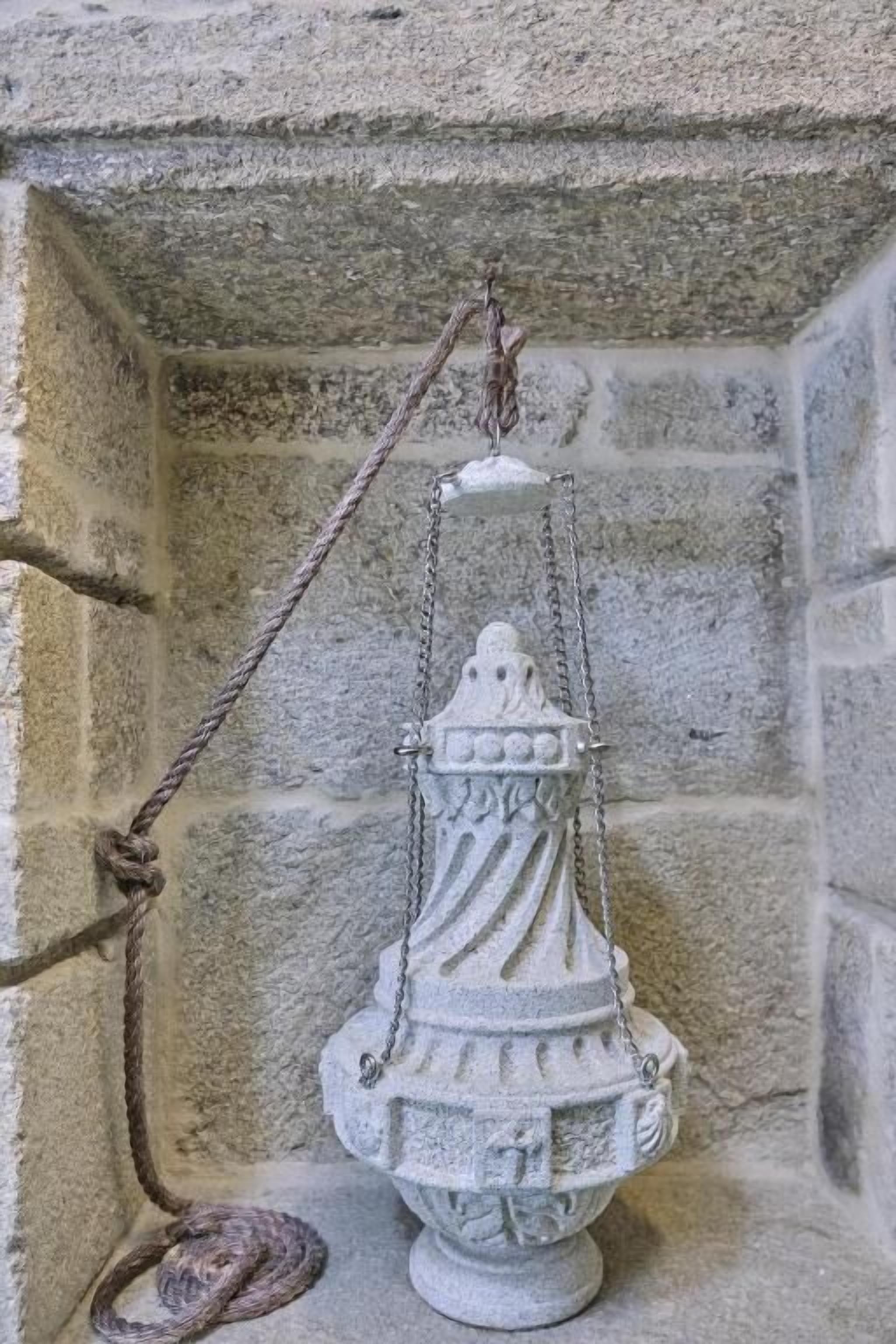 A stone lantern hanging in a corner with a rope.