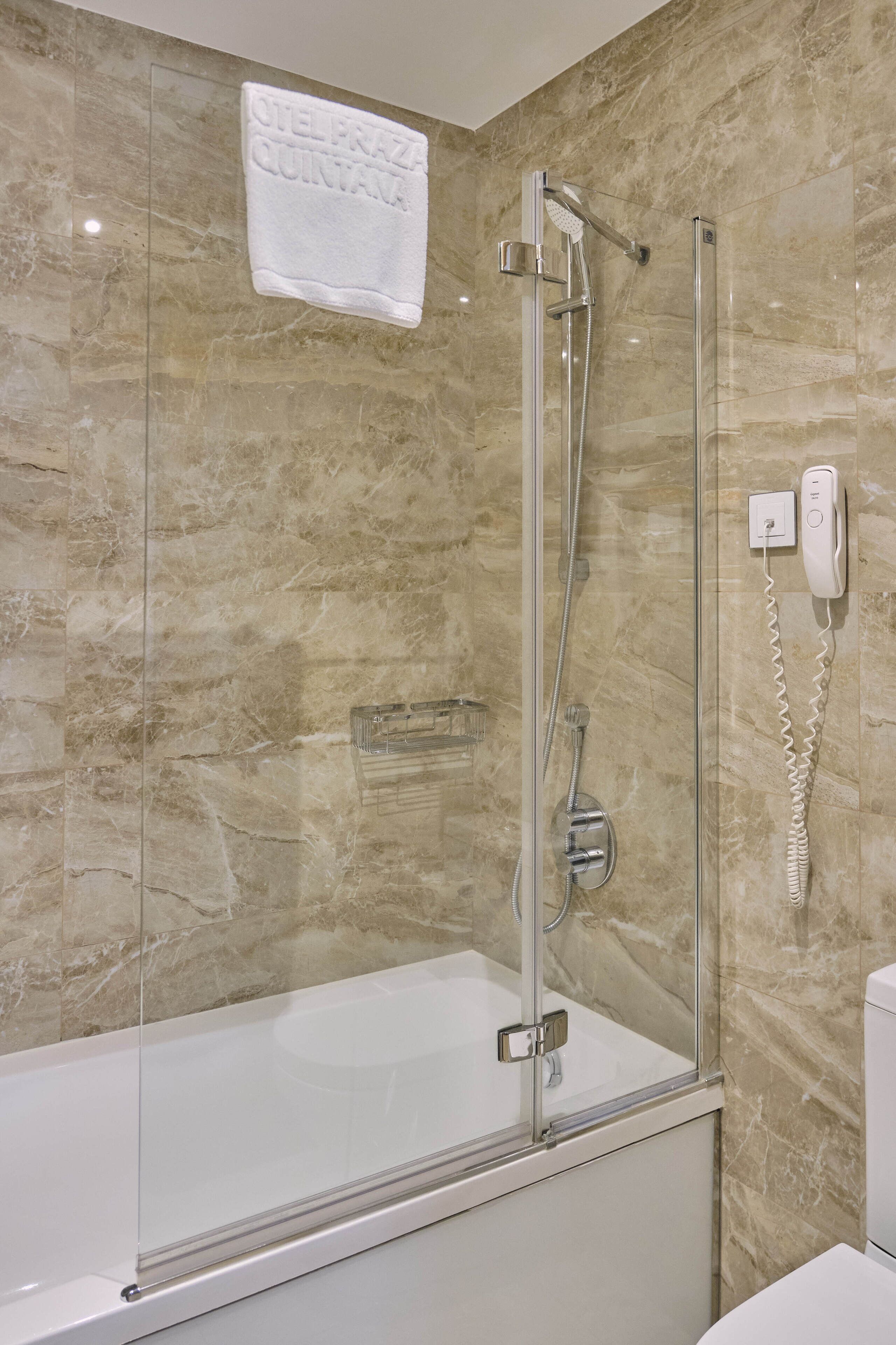 Ein modernes Badezimmer mit einer gläsernen Duschkabine, einer weißen Badewanne und einer Marmorwand.