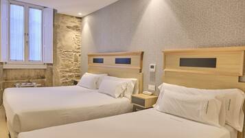 Ein Hotelzimmer mit zwei Betten, einer Wand mit Steinverkleidung und einem Fenster mit Vorhängen.