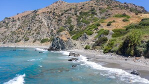 A coastal landscape with clear blue waters, rocky terrain, and sparse vegetation. - Preveli Villas (Agios Vasileios)
