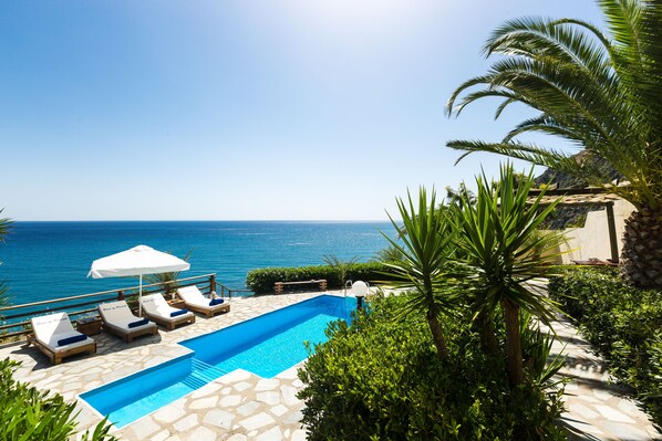 Una piscina al aire libre, sombrillas, sillones reclinables de piscina