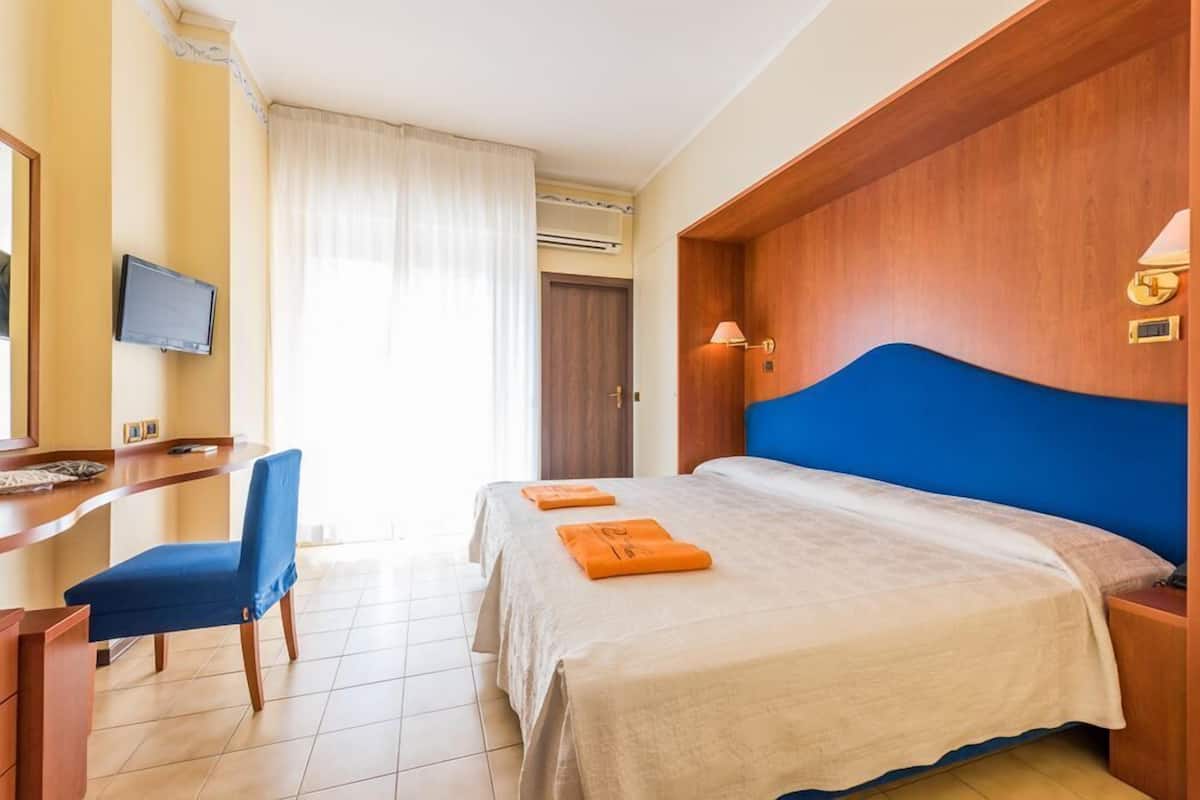 Ein Hotelzimmer mit Bett, Schreibtisch, Stuhl und Fernseher.