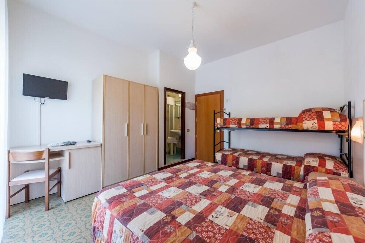 Ein Schlafsaalzimmer mit Etagenbetten, einem Schreibtisch, einem Stuhl und einem Fernseher.