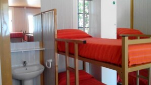 Un dormitorio con literas, un lavamanos y un espejo.