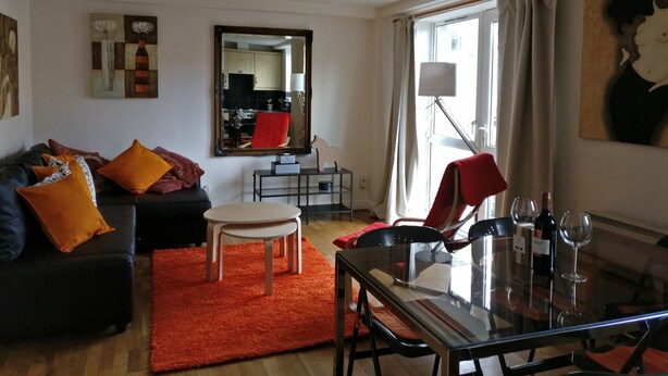 Un salon moderne avec un canapé, une table à manger et un tapis rouge.