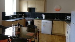 Une cuisine avec des meubles de rangement en bois, une cuisinière, un lave-vaisselle et un four à micro-ondes.