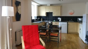 Une cuisine compacte avec des meubles en bois, un four à micro-ondes, un lave-vaisselle et une chaise rouge.