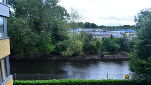 A river with a bridge, surrounded by greenery and a building in the background. - MetroStays - Riverside Apartment (Dublin)
