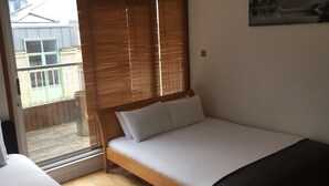 A bedroom with a bed, wooden blinds, a window, and a door leading to a balcony. - MetroStays - Stephen's Green 7-3 (Dublin)