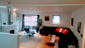 A modern living room with a black sofa, a wooden coffee table, a black lounge chair, and a potted plant. - MetroStays - Stephen's Green 7-3 (Dublin)