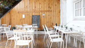 A restaurant with white chairs and tables, a chalkboard menu, and a wooden wall with string lights. - Casona Recoleta (Santiago)