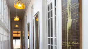 A hallway with wooden flooring, white walls, and a large framed artwork on the right. - Casona Recoleta (Santiago)