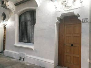 A building with a wooden door, a barred window, and a number '287' on the wall. - Casona Recoleta (Santiago)
