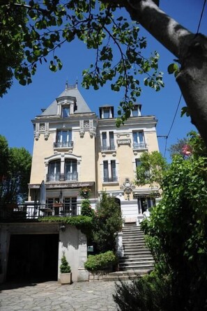 A large, historic building with multiple stories, a prominent entrance, and a staircase leading to the main entrance. - Hôtel Terminus (Cahors)