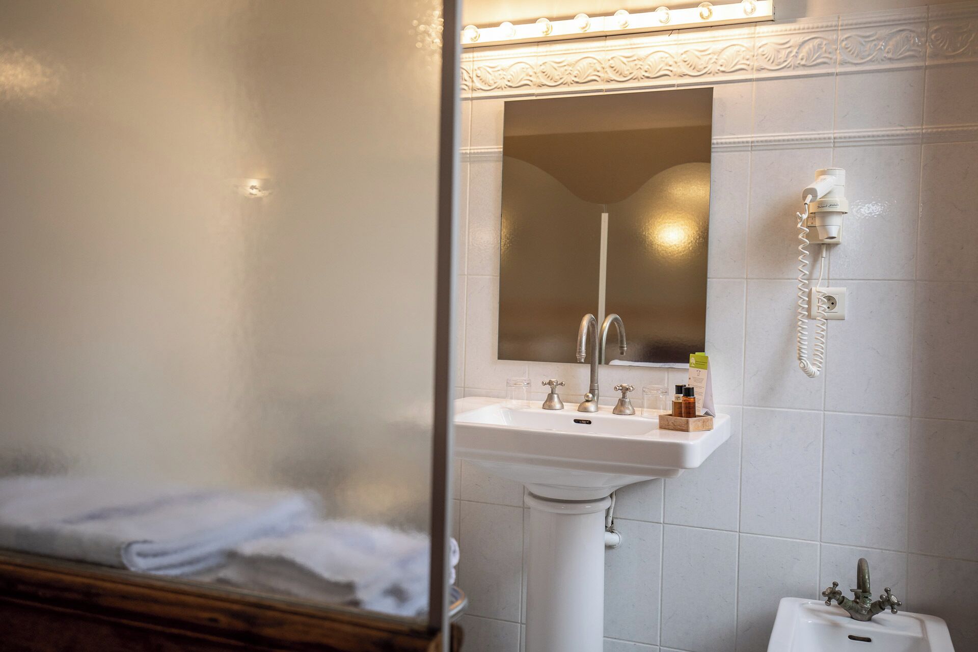 A bathroom with a sink, mirror, and a telephone.