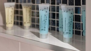 A row of bath and shower gel tubes on a shelf with a tiled backsplash. - MetroStays - Stephen's Green 7-1 (Dublin)