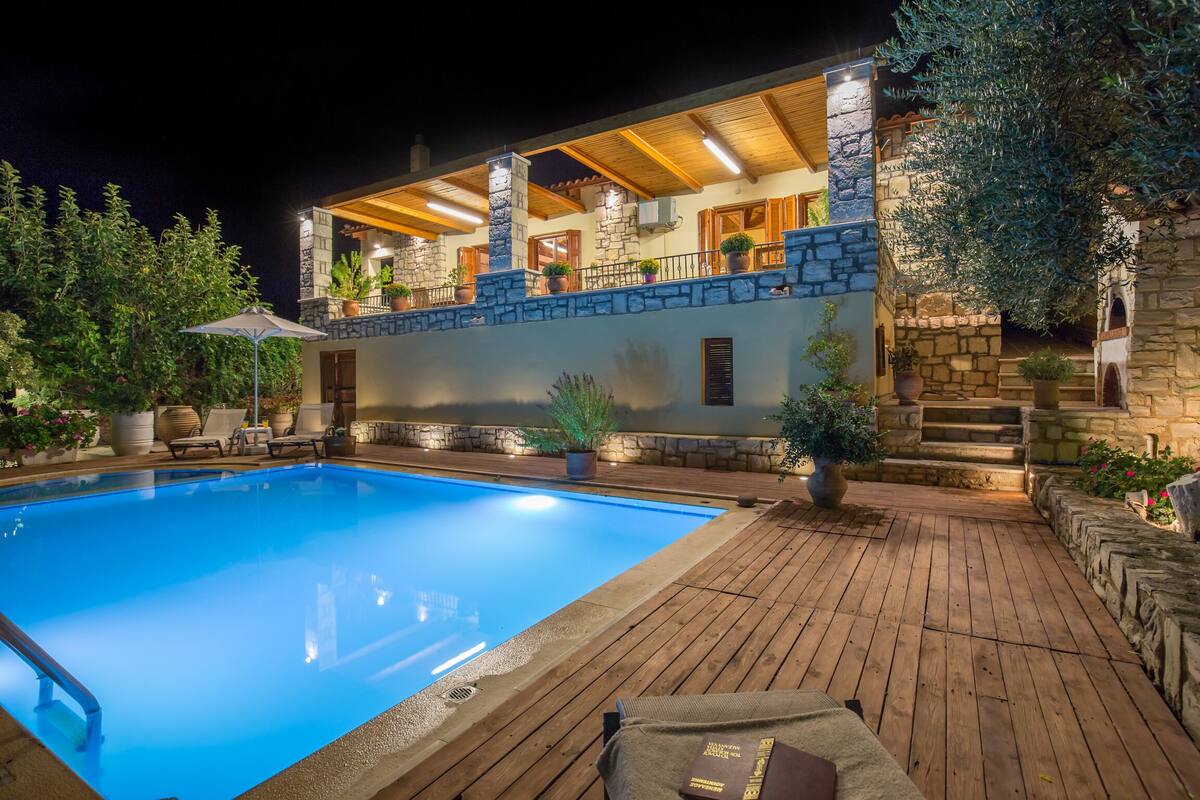 Un espace aménagé au bord de la piscine, avec une terrasse en bois, des murs en pierre et des plantes en pot.